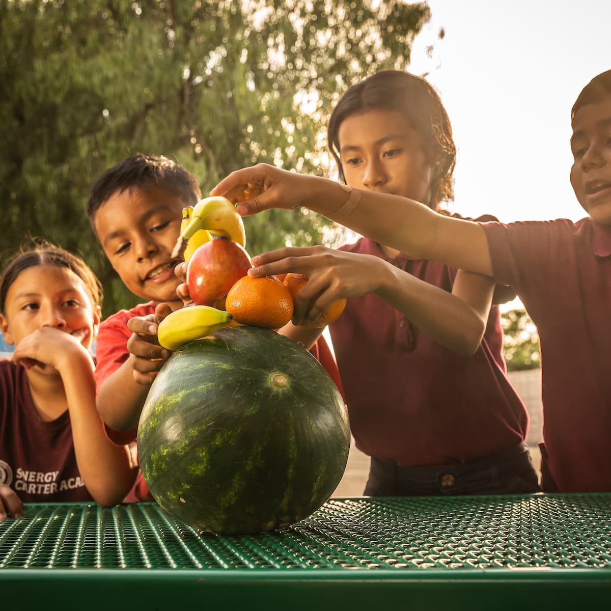 kids balancing fruit on picnic table outdoors
