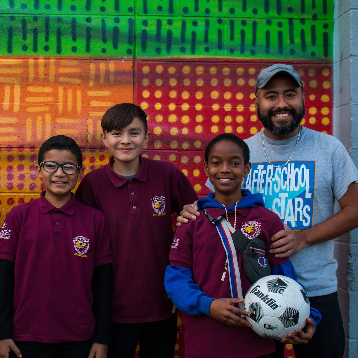 Coach and soccer players standing in front of colorful wall