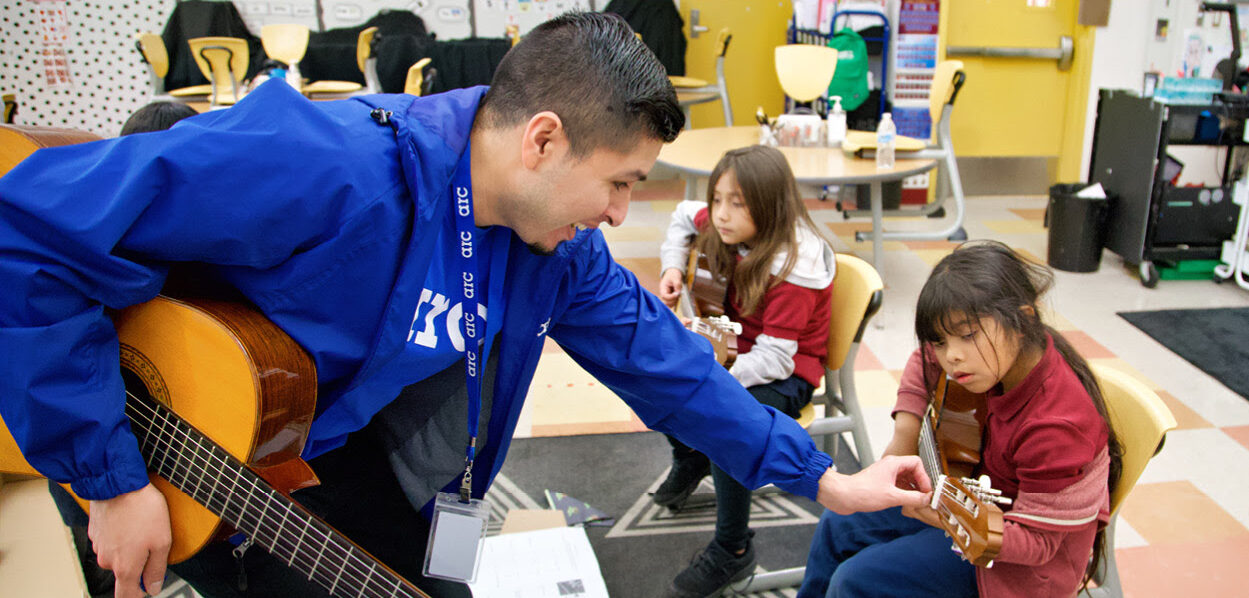 Mentor helps student tune guitar